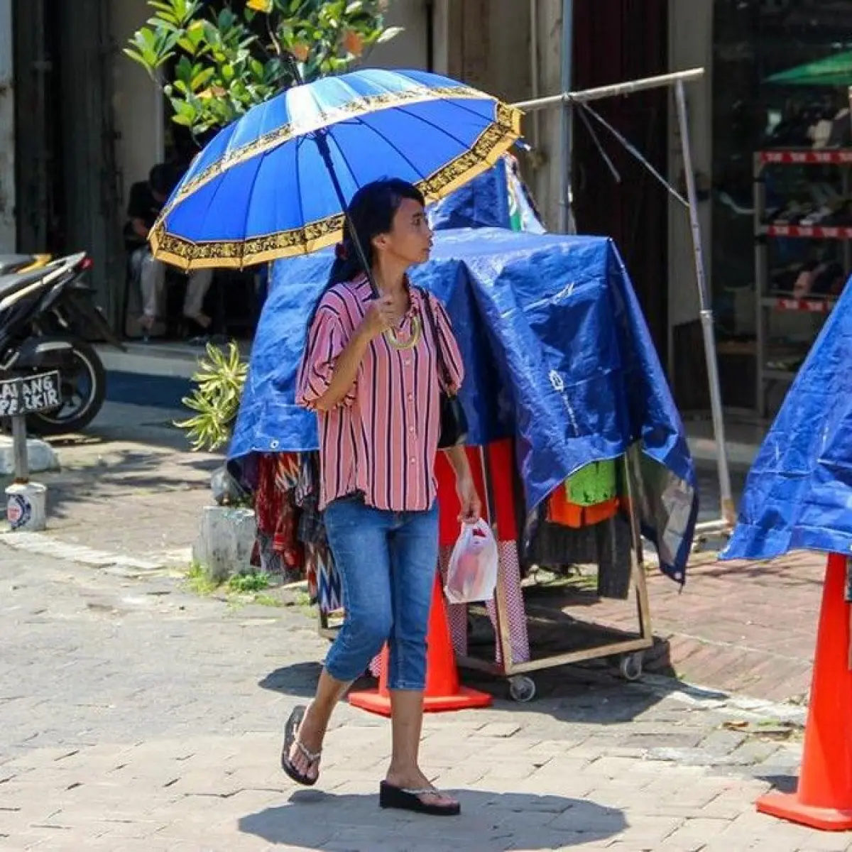 Warga berjalan menggunakan payung di kawasan Pasar Baru, Jakarta Pusat, Selasa (17/3/2026). Foto: Muhammad Farrel / detikfoto